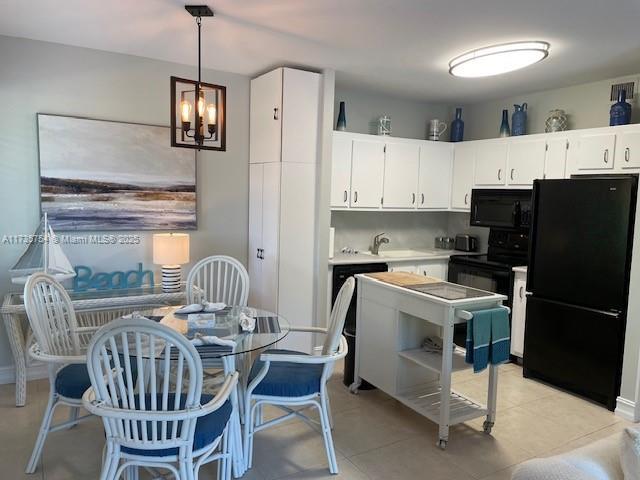 kitchen featuring pendant lighting, white cabinetry, decorative backsplash, light tile patterned floors, and black appliances