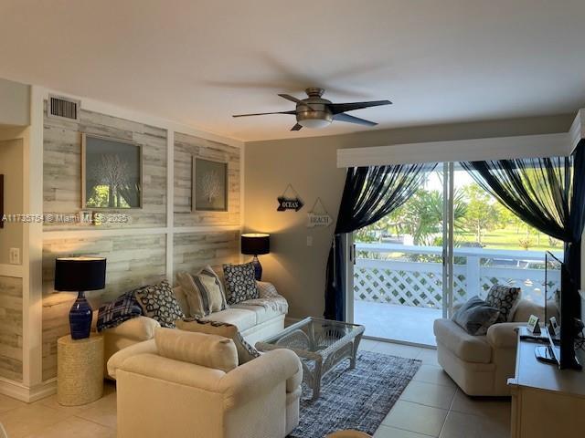 tiled living room with ceiling fan and wood walls