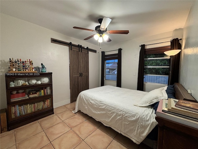 bedroom featuring light tile patterned floors, a barn door, and ceiling fan