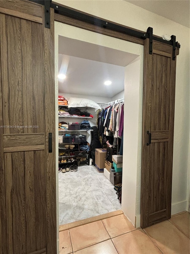 spacious closet featuring tile patterned floors and a barn door