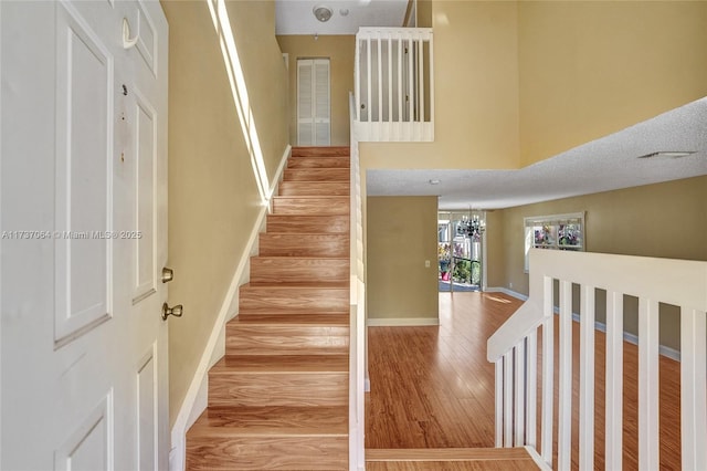 stairs featuring hardwood / wood-style floors and a notable chandelier