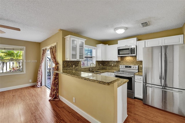 kitchen featuring stone counters, white cabinetry, sink, kitchen peninsula, and stainless steel appliances