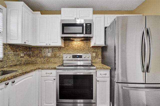 kitchen featuring dark stone countertops, stainless steel appliances, backsplash, and white cabinets