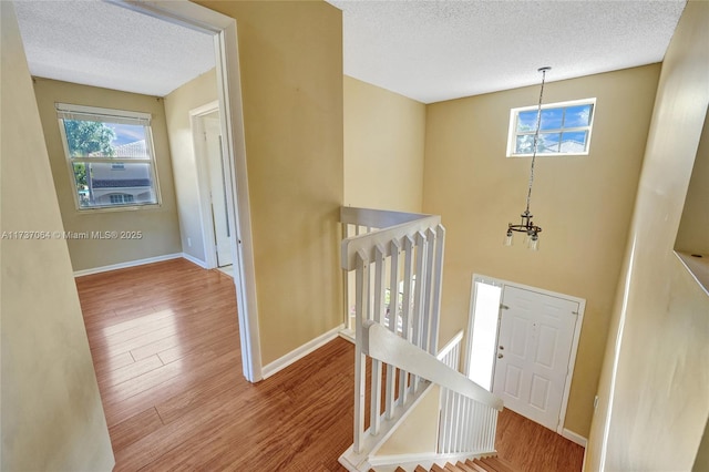 staircase with a chandelier, hardwood / wood-style floors, and a textured ceiling