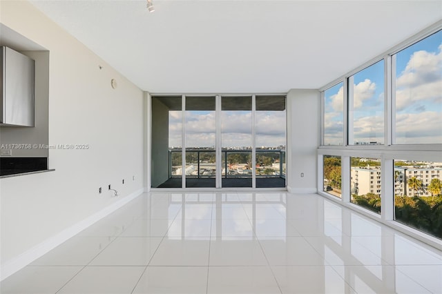 tiled empty room with a healthy amount of sunlight and a wall of windows