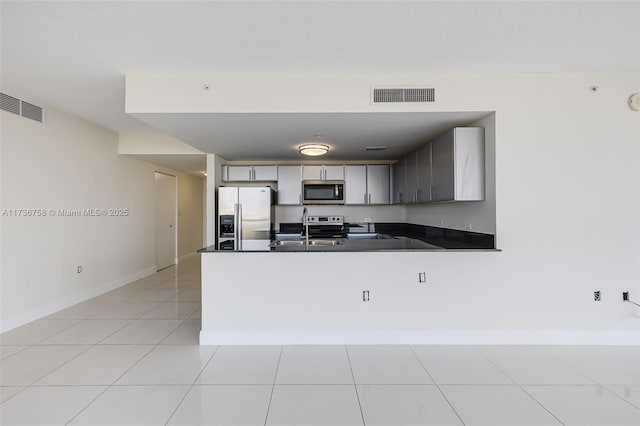 kitchen with light tile patterned flooring, sink, appliances with stainless steel finishes, gray cabinets, and kitchen peninsula