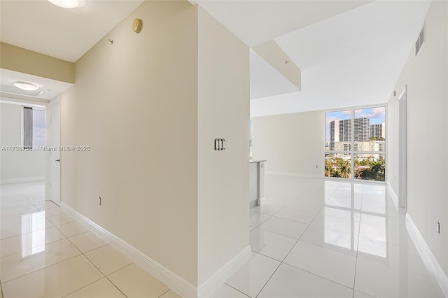 hall with light tile patterned flooring and a wall of windows