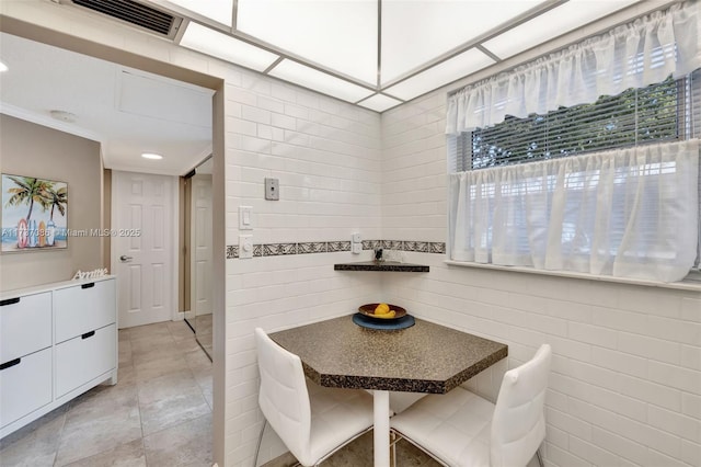 dining space featuring tile walls and light tile patterned floors