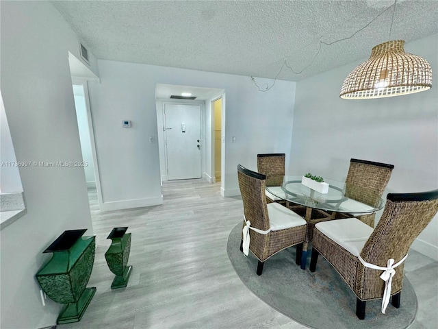 1000 Parkview Dr Unit 202, Hallandale Beach, FL 33009 - dining room featuring a textured ceiling, wood finished floors, visible vents, and baseboards