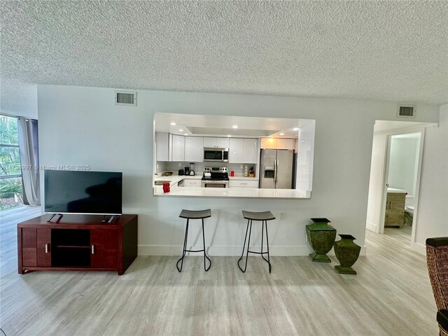 1000 Parkview Dr Unit 202, Hallandale Beach, FL 33009 - kitchen with visible vents, appliances with stainless steel finishes, a peninsula, light countertops, and white cabinetry