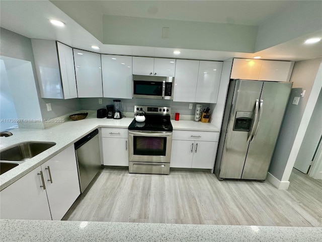 1000 Parkview Dr Unit 202, Hallandale Beach, FL 33009 - kitchen with light wood-style flooring, appliances with stainless steel finishes, light countertops, white cabinetry, and a sink