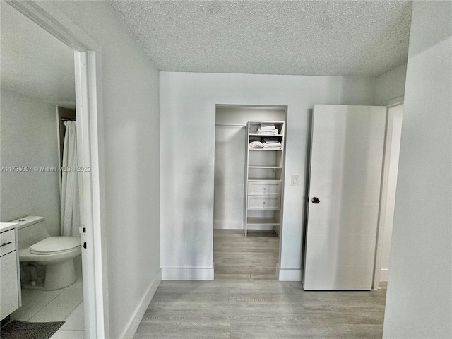1000 Parkview Dr Unit 202, Hallandale Beach, FL 33009 - bathroom featuring toilet, a textured ceiling, baseboards, and wood finished floors