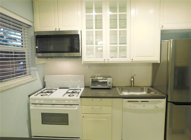 kitchen with tasteful backsplash, appliances with stainless steel finishes, sink, and white cabinets