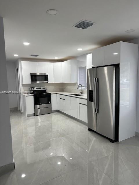 kitchen featuring stainless steel appliances, white cabinetry, and sink