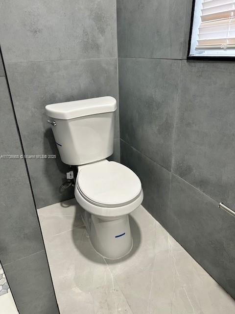 bathroom featuring tile walls, tile patterned floors, and toilet