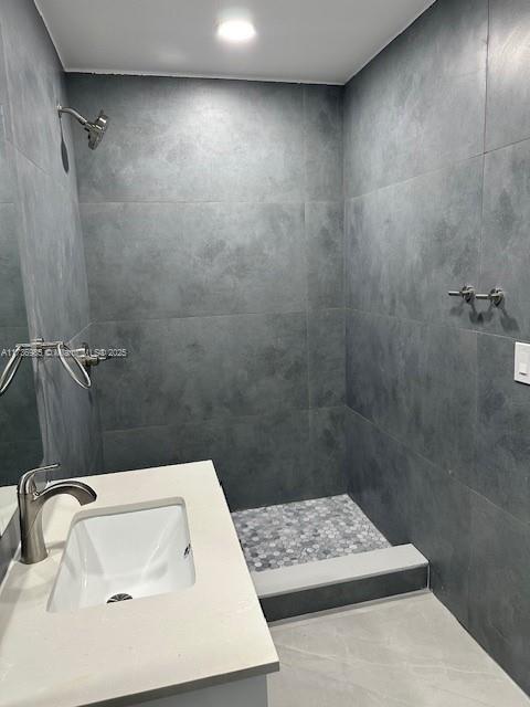 bathroom with vanity and a tile shower