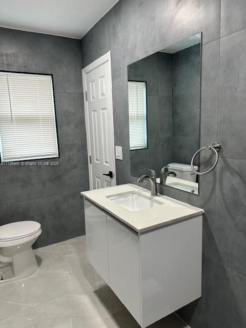 bathroom with vanity, toilet, and tile walls