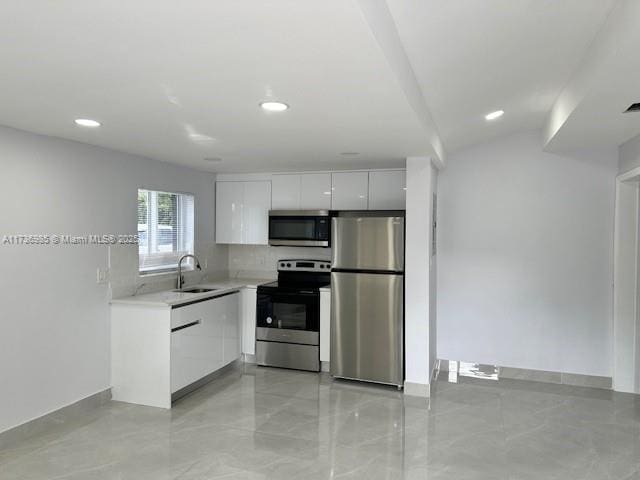 kitchen with stainless steel appliances, white cabinetry, sink, and decorative backsplash