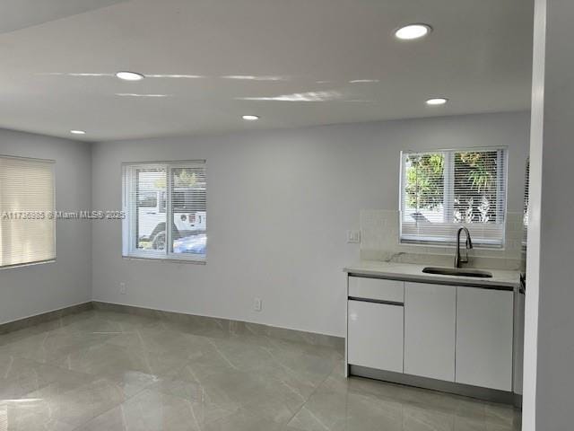 kitchen featuring white cabinetry, plenty of natural light, sink, and backsplash