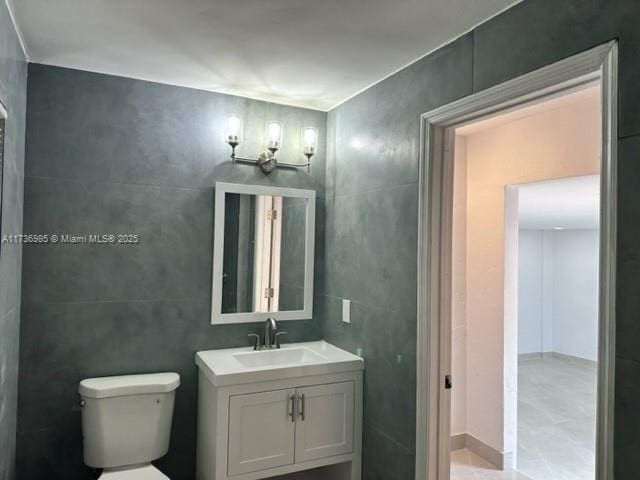 bathroom with vanity, toilet, and tile walls