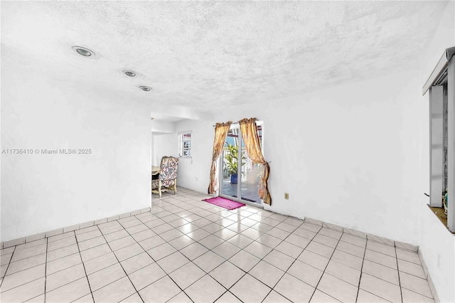 tiled empty room with a textured ceiling