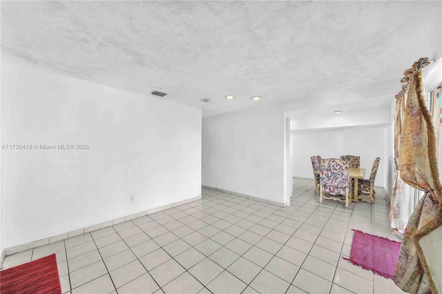 tiled empty room featuring a textured ceiling