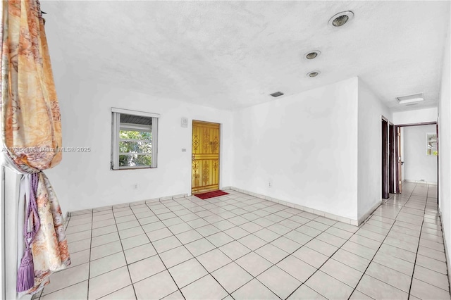 spare room with light tile patterned floors and a textured ceiling