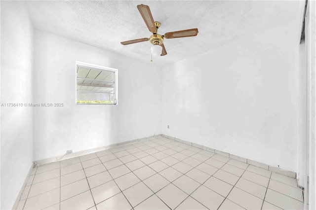 empty room with ceiling fan, light tile patterned floors, and a textured ceiling