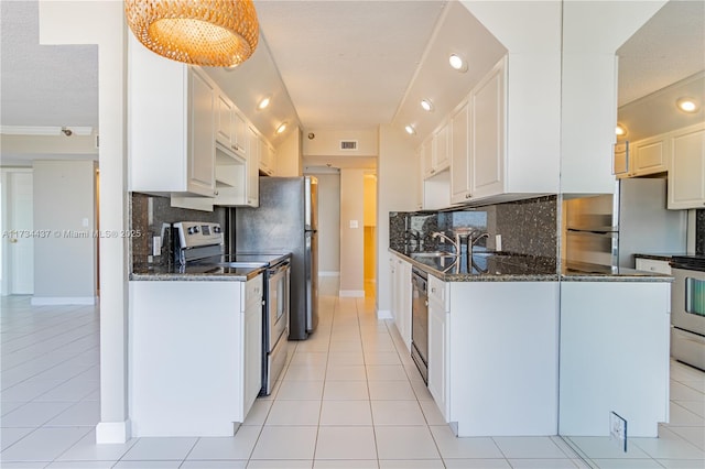 kitchen featuring white cabinetry, appliances with stainless steel finishes, and dark stone countertops