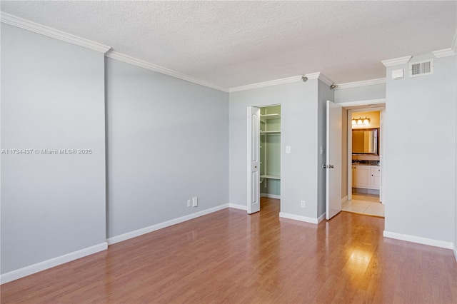 empty room featuring ornamental molding, a textured ceiling, and light hardwood / wood-style floors