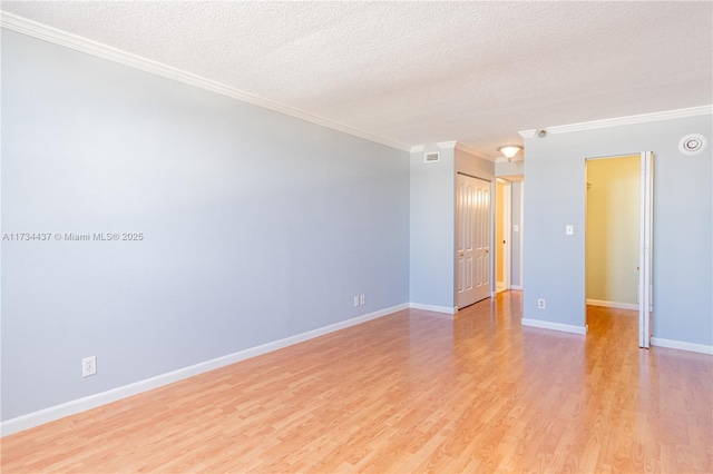 unfurnished room with ornamental molding, a textured ceiling, and light wood-type flooring