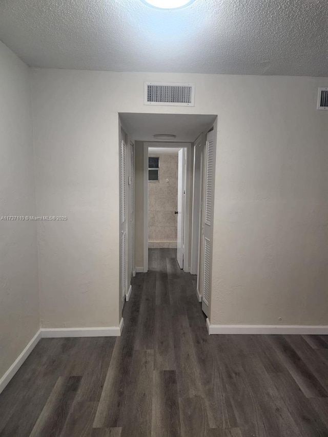 corridor featuring dark hardwood / wood-style flooring and a textured ceiling