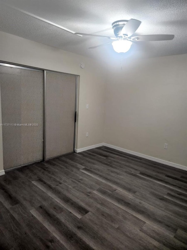 unfurnished bedroom featuring dark wood-type flooring, ceiling fan, and a textured ceiling