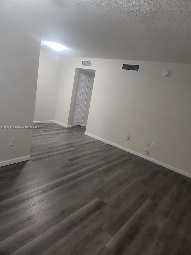 spare room featuring dark wood-type flooring and a textured ceiling