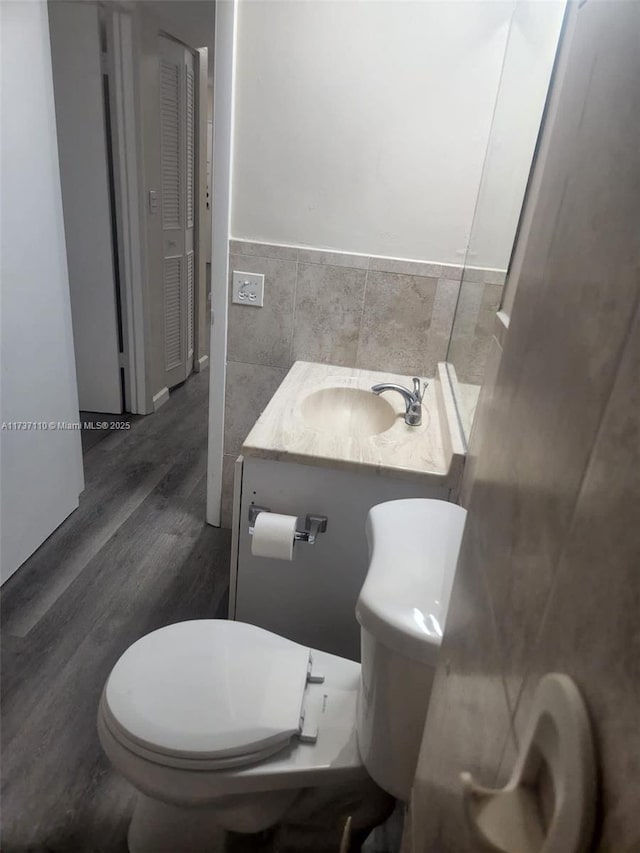 bathroom with hardwood / wood-style floors, vanity, tile walls, and toilet