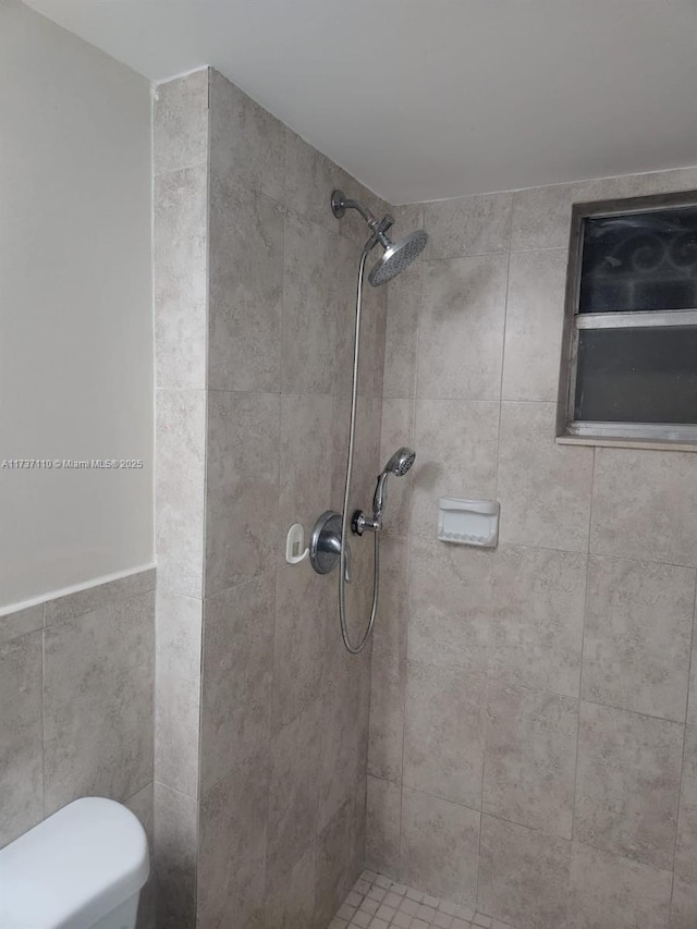 bathroom featuring a tile shower and toilet