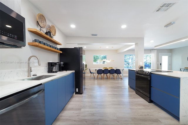 kitchen with sink, light wood-type flooring, stainless steel appliances, and blue cabinetry