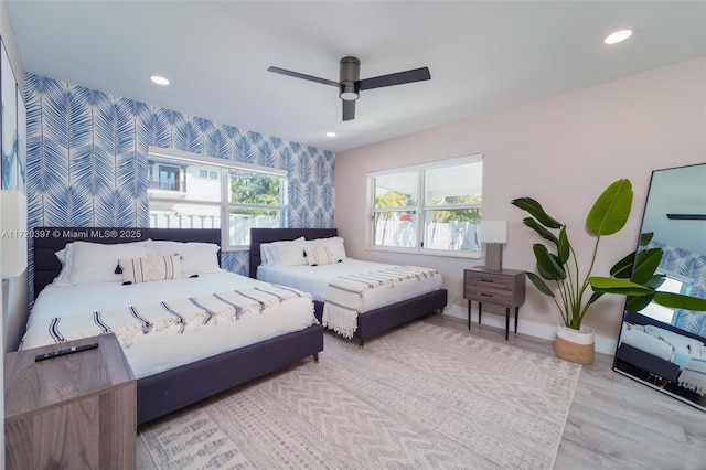 bedroom featuring ceiling fan, light hardwood / wood-style floors, and multiple windows