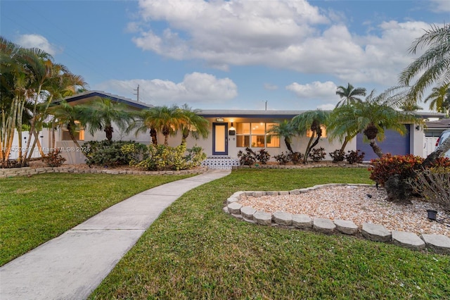 ranch-style home featuring a garage and a front lawn