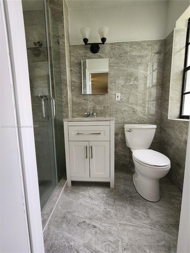 bathroom with an enclosed shower, vanity, tile walls, and toilet