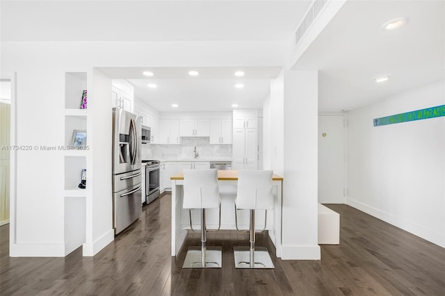 kitchen with sink, a kitchen breakfast bar, kitchen peninsula, stainless steel appliances, and white cabinets