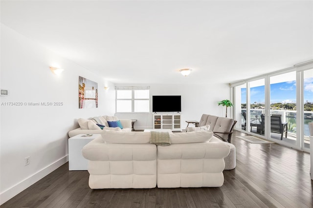 living room featuring a wealth of natural light, dark wood-type flooring, and floor to ceiling windows