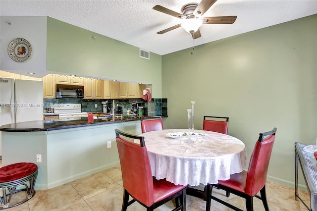 dining area with light tile patterned flooring, ceiling fan, and a textured ceiling