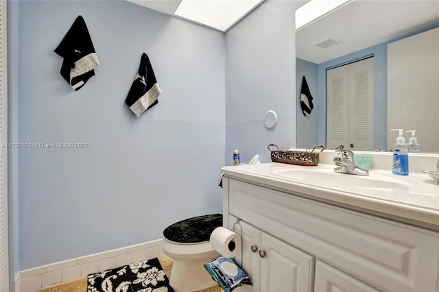 bathroom featuring vanity, a skylight, and toilet