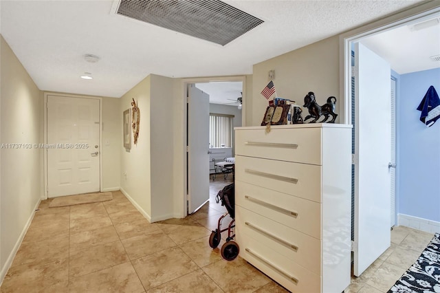 hall featuring light tile patterned floors and a textured ceiling