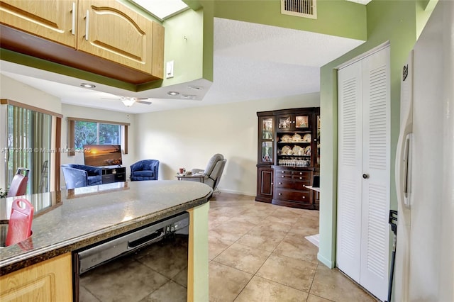 kitchen featuring white refrigerator, light tile patterned flooring, black dishwasher, and light brown cabinetry