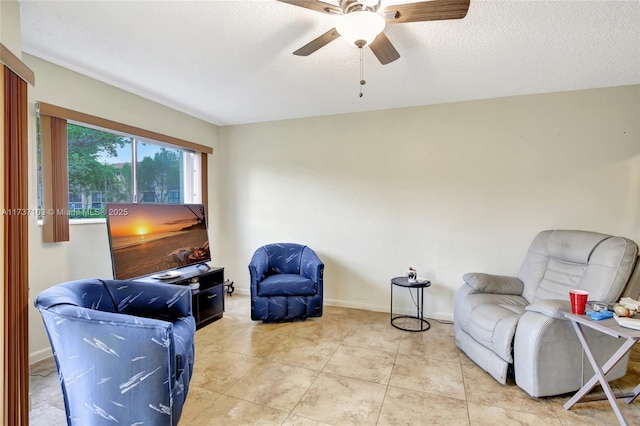 living area featuring light tile patterned flooring, ceiling fan, and a textured ceiling