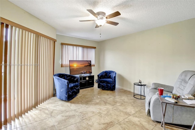 sitting room with ceiling fan, light tile patterned floors, and a textured ceiling