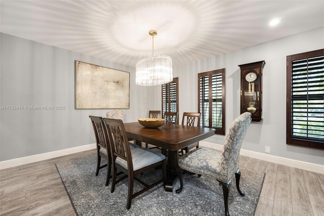 dining room with a wealth of natural light, baseboards, an inviting chandelier, and wood finished floors