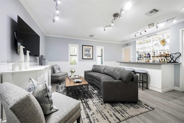 living area with a bar, crown molding, wood finished floors, and visible vents